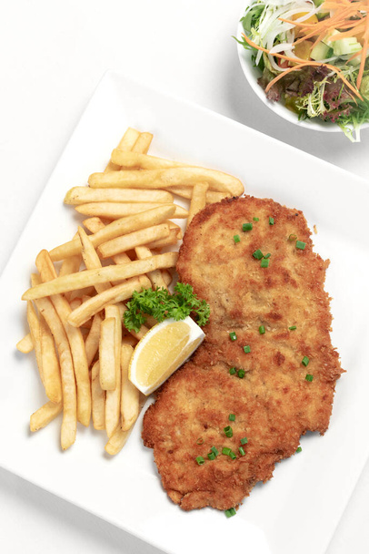 german breaded pork schnitzel with french fries on white studio background - Photo, Image