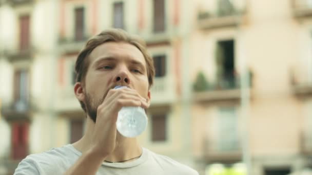 Junger Mann trinkt und genießt eine Flasche kaltes Wasser - Filmmaterial, Video