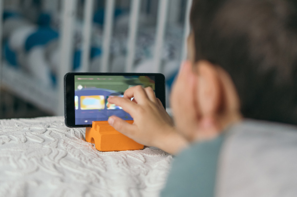 foyer sélectif de petit garçon touchant l'écran du smartphone tout en regardant leçon en ligne
 - Photo, image