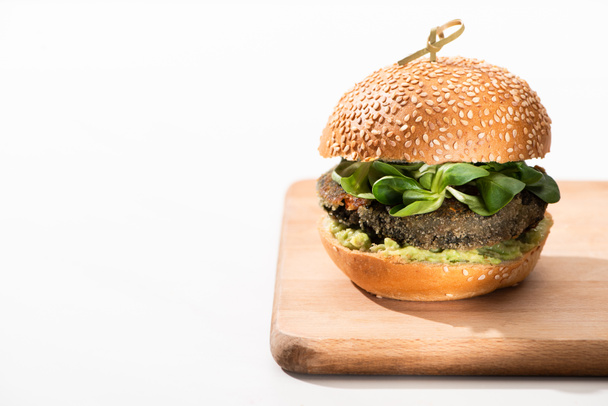 delicious green vegan burger with microgreens and mashed avocado on wooden boar on white background - Photo, Image