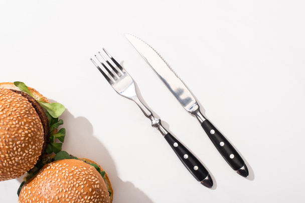 vista superior de hambúrgueres vegan perto de garfo e faca no fundo branco
 - Foto, Imagem