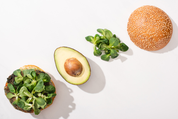 Ansicht von veganem Burger mit Avocado und Mikrogemüse auf weißem Hintergrund - Foto, Bild