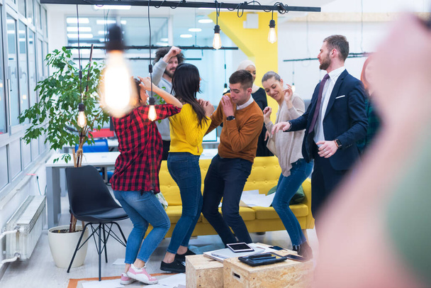 若いビジネスチームはオフィスで良い仕事を祝う。仕事が成功した後、共同作業スペース内で踊る若い同僚のグループ. - 写真・画像