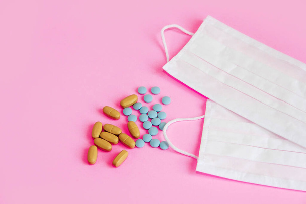 witte medische maskers en tabletten op roze achtergrond - Foto, afbeelding