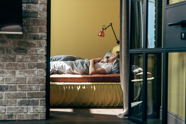 selektywne skupienie się mężczyzny i kobiety odpoczywających w nowoczesnej sypialni - Zdjęcie, obraz