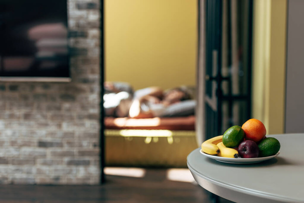 selective focus of fresh and ripe fruits on table near couple in bedroom  - Fotoğraf, Görsel