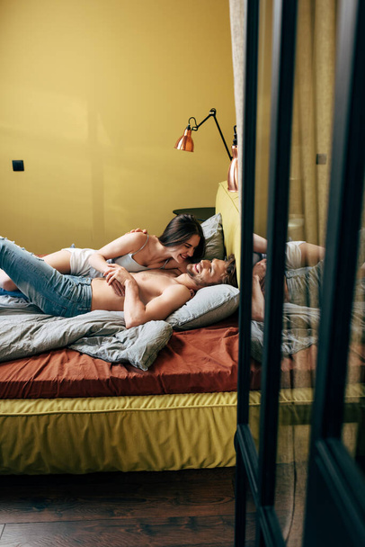enfoque selectivo de hombre alegre y sin camisa riendo con la mujer en el dormitorio
  - Foto, Imagen