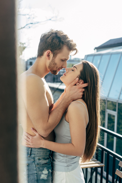 selective focus of shirtless man hugging girlfriend on balcony  - Zdjęcie, obraz