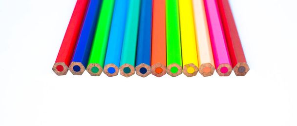 Row of different color wood pencil crayons placed on a white isolated background - Photo, Image