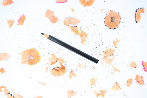 Crayon crayon en bois de couleur noire placé à côté de quelques copeaux de crayon normaux éparpillés
 - Photo, image