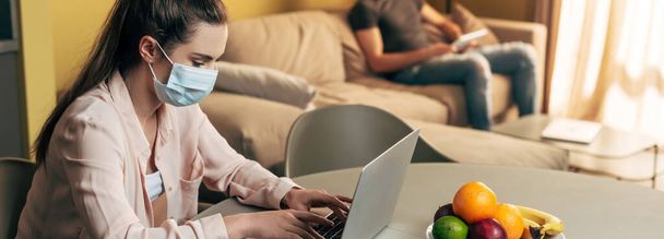 panoráma felvétel a szabadúszó orvosi maszk laptop közelében ember digitális tabletta otthon  - Fotó, kép
