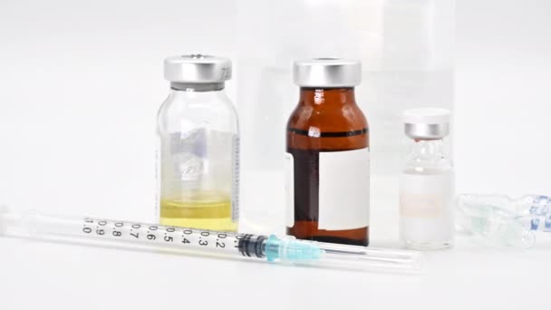 コロナウイルスパンデミック、人々の予防接種の概念。バイアルとワクチン注射器白い背景に薬を閉じ、左から右にドリーショット. - 映像、動画