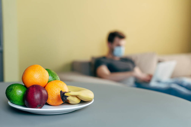 selective focus of fruits on plate near freelancer working from home  - 写真・画像