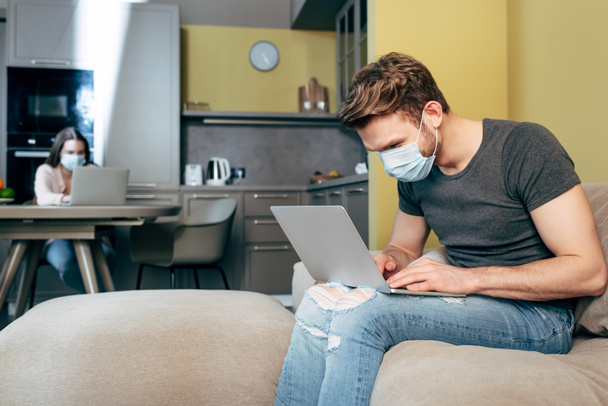 selective focus of freelancer in medical mask working from home near girlfriend  - Фото, зображення