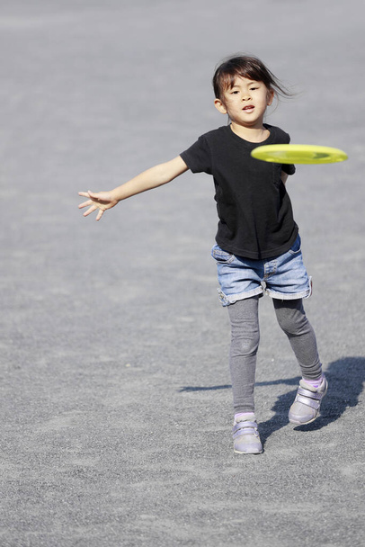 Японская девочка играет на летающем диске (5 лет)
) - Фото, изображение