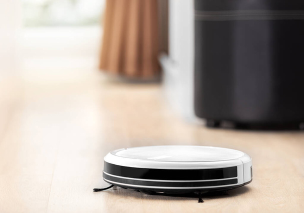 white robot vacuum machine auto clean in bedroom, livingroom of smart home and house instead of human by innovation technology for home and order by smart phone or remote - 写真・画像