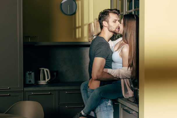 bearded man kissing seductive girl in kitchen  - Foto, Imagem