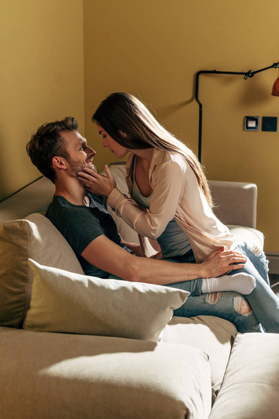 selective focus of girl touching face of happy bearded man in living room  - Zdjęcie, obraz