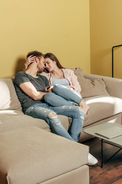 couple hugging and sitting on sofa in living room  - 写真・画像