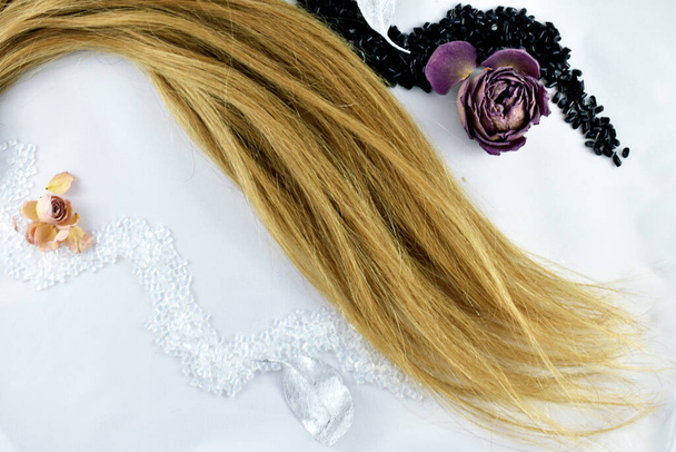 streng van blond haar op een witte achtergrond - Foto, afbeelding
