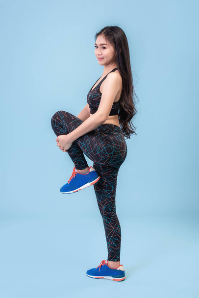 Молодые азиатские девушки носят леггинсы для упражнений на пастельно-голубой сцене студии
. - Фото, изображение