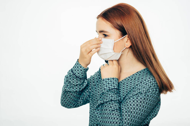 Young woman puts on a medical face mask, protection against viruses and bacteria Covid-19 Coronavirus. isolated against a white background - Photo, image