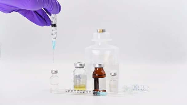 Farmacêutico Cientista segurando seringa injetando líquido no frasco para injetáveis. Pesquisa de vacinas contra o coronavírus. Frascos de medicamentos em fundo branco
. - Filmagem, Vídeo