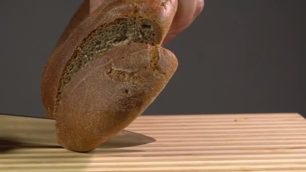 Closeup άποψη του αρσενικού σεφ τεμαχισμού ψωμί σε ξύλο κοπής του σκάφους. Κοπή ψωμιού. - Πλάνα, βίντεο