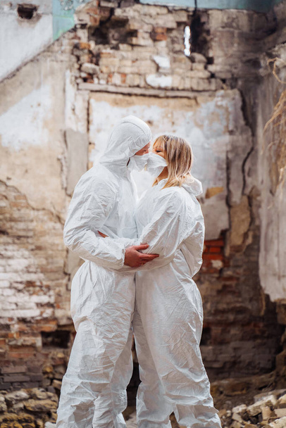 Orvosok védőruhában és maszkban csókolóznak egy lerombolt épület romjain. Örülnek, hogy elmúlt a veszély, és megmentették az embereket. Csókolózni a túlzott érzelmektől. - Fotó, kép