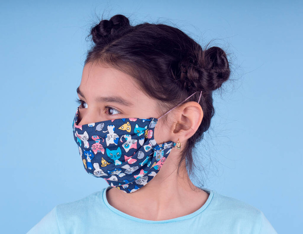 Little funny girl with a collorful mask. Excitement and fascination concept. Close up portrait. Studio shot over blue background. foolish grimaces comical crazy gesture. Funny expression. Covid-19 . little doctor. stay at home. stay safe - Photo, Image