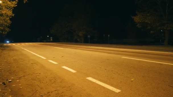 Młody człowiek szybko ściga się na motocyklu sportowym przez pustą ulicę nocną. Motocyklista jadący na dużych prędkościach wzdłuż wieczornej drogi miejskiej. Gość lubi szybkość. Widok z niskiego kąta - Materiał filmowy, wideo