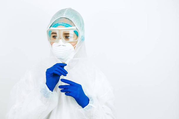 portrait of tired doctor after shift in the hospital. The doctor in protective clothing - glasses, mask, gloves on white background. The doctor treating patients with coronavirus. Covid-2019 - Photo, image
