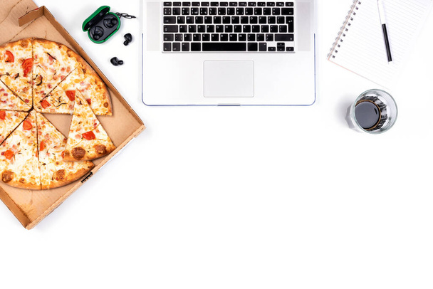 Pizza in einem Karton und Laptop auf weißem Hintergrund. Kopieren Sie Platz für Ihren Text. Draufsicht, flache Lage. Konzept Essen zum Mitnehmen - Foto, Bild