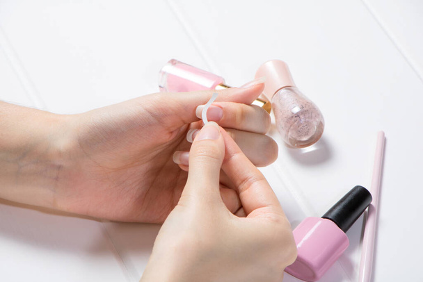 A woman glues stickers on her nails for French manicure. Manicure. The girl applies nail Polish. Nail salon, procedure, SPA. Home nail care. Manicure tools. Beauty, nail art, Glamour. - 写真・画像