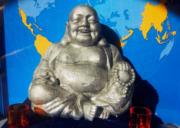 άγαλμα του γελαστού Βούδα μπροστά στον μπλε παγκόσμιο χάρτη - Φωτογραφία, εικόνα
