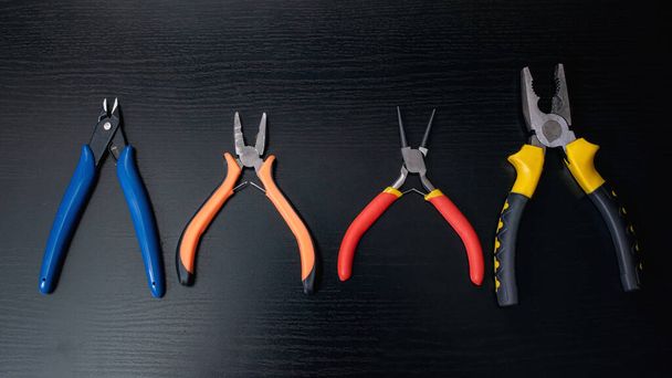 Pliers, tools on a black wooden table close up - Фото, изображение