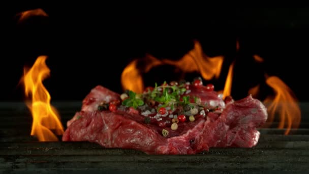 Super slow motion of beef steak on grill with falling spices, black background. Filmed on high speed cinema camera, 1000 fps - Кадри, відео