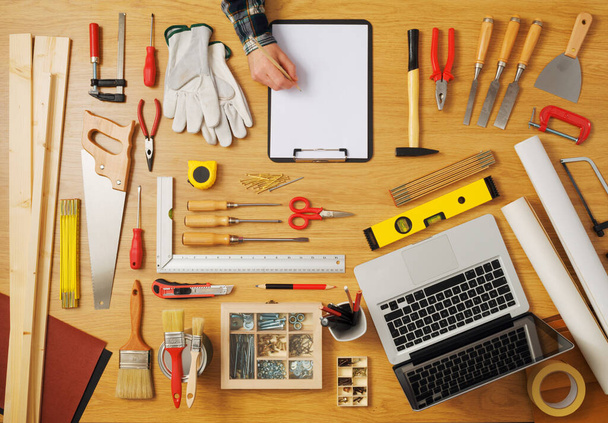 Male hand sketching on a white clipboard top view, DIY work tools all around, carpentry and hobby concept - 写真・画像