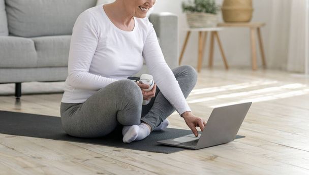 Senior Lady Preparing For Training At Home, Browsing Online Tutorials On Laptop - Φωτογραφία, εικόνα