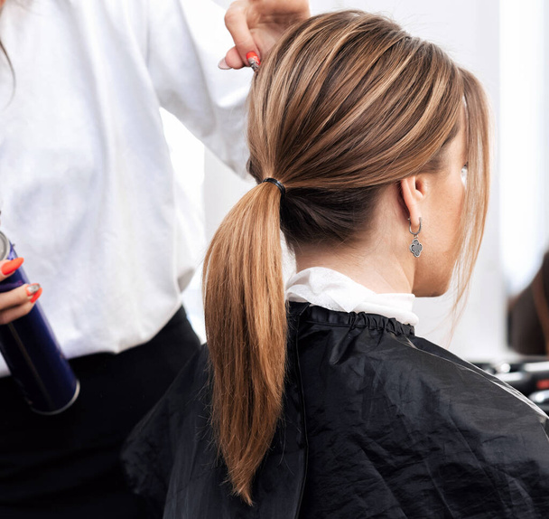 fodrász teszi a frizura egy nő világos barna hosszú haj - Fotó, kép
