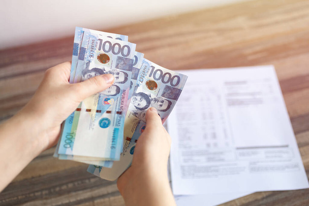 Mains tenant des billets en espèces d'un millier de peso philippin payant les factures, le paiement ou le salaire. Fond blanc, gros plan
 - Photo, image