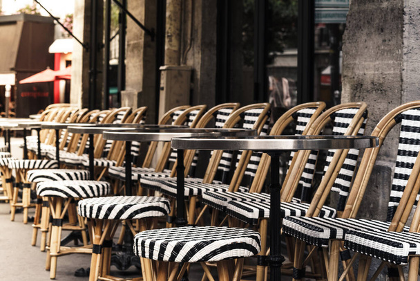 Café parisino con sillas y mesas blancas y negras alineadas en la acera
 - Foto, imagen