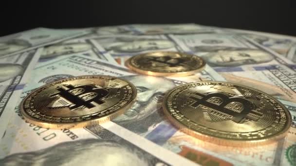 Three Bitcoins BTC are rotating on the table with 100 US dollars. Black background. Bitcoin is the firs decentralized currency in the modern world. Great investment in future with with the possibility - Felvétel, videó