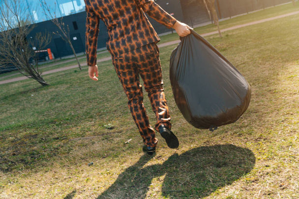 Adam dikiz aynasından büyük siyah çantalı. Bir yaz günü sokakta çöp toplama kavramı. - Fotoğraf, Görsel