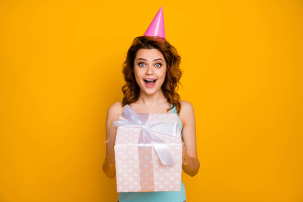 Photo of pretty funny lady hold large giftbox hands unexpected secret admirer present wear pink paper birthday cap casual teal tank-top isolated bright yellow color background - Φωτογραφία, εικόνα