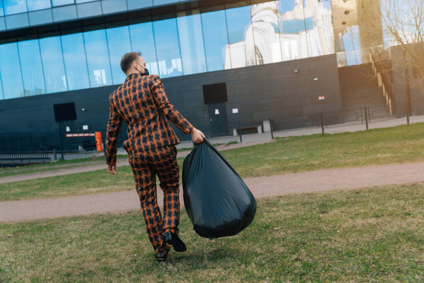 Rear view of a european man carries garbage bags into containers. The concept of cleaning of the territory park. - Foto, immagini