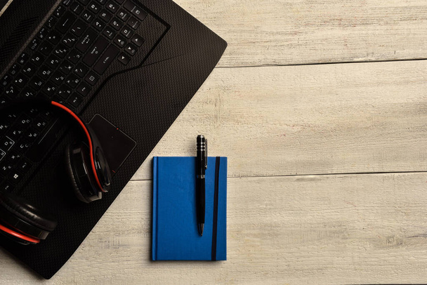 Laptop, notebook and headphones  lie on a wooden table - Φωτογραφία, εικόνα