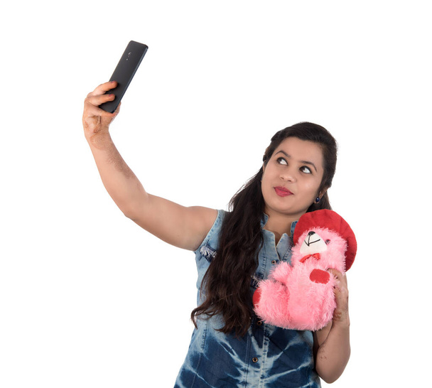 Woman taking picture or selfie with mobile phone and holding teddy bear - Foto, Imagen