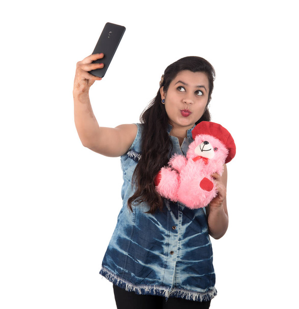 Woman taking picture or selfie with mobile phone and holding teddy bear - Foto, Imagen