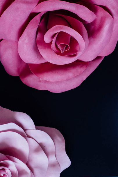 黒を基調としたトップオグのイメージの巨大なダークピンクの手作りのファミランの花とライトピンクの花びら。縦配置。下部のテキストスペースを閉じます - 写真・画像